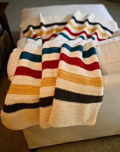 a crocheted blanket sitting on top of a white couch