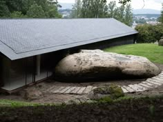 a large rock sitting in the middle of a yard next to a building with a roof