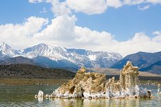 some very pretty rocks in the water with mountains in the backgrouds behind them