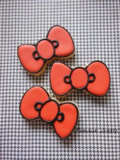 three decorated cookies sitting on top of a checkered tablecloth covered table with black and red bows