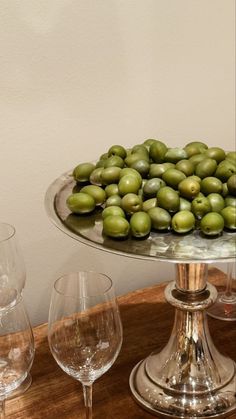 there are many glasses on the table and one is filled with green olives as well