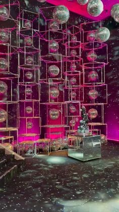 the stage is set up for an event with pink lighting and silver balls hanging from the ceiling