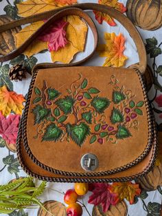 A beautiful vintage 70's brown tooled leather satchel by ACA Smith Leathercraft. Is a tan brown shade with a metal fastening to open. Has been hand tooled with a leaves and raspberry design and then handpainted by me in specialist leather paints and finished with a specialist varnish to protect the design. Has leather thong stitching around the outside. Has a cross body strap. Perfect Autumn boho bag. There are some scuffs to the back and some erratic 70's child has marked on the inside flap (pi Tooled Leather Bag, Handpainted Bags, Raspberry Fruit, Brown Shade, Leather Paint, Boho Fall, Tooled Leather, Boho Bag, Women's Handbags