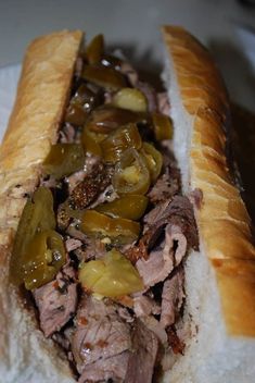 a close up of a sandwich with meat, peppers and onions on it's bun