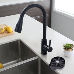 a kitchen sink with a black faucet and two lemons on the counter