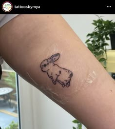 a person with a tattoo on their arm that has a small rabbit drawn on it