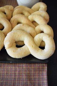 several pretzels on a black plate next to a cup