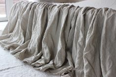 an unmade bed with white sheets and pillows