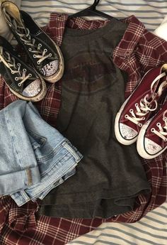 two pairs of converse shoes are sitting on top of a plaid shirt and jean shorts