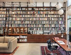 a living room filled with lots of books on top of a book shelf next to a couch