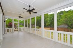 an empty room with white walls and ceiling fans on the windows, and wood floors