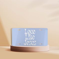 a blue license plate with the words love like jesus on it sitting on a table