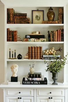 a white book shelf filled with lots of books and vases on top of it