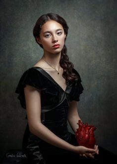 a woman in a black dress holding a red heart