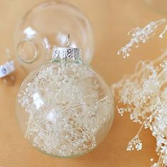 a glass ornament filled with white flowers on top of a table next to a vase