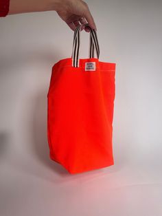 The Carry-Some, not for Carrying All, in eye-catching neon orange. Small but big enough to carry the essentials -- a book, wallet, phone, water bottle. For a light day out! Main fabric is water-resistant marine upholstery nylon; Handles made of nylon ribbon.  Individually prepared and manufactured in NYC, this is made to order - shipment can be expected 3 weeks after the order is placed. Casual Orange Nylon Bag, Eco-friendly Orange Vacation Bag, Eco-friendly Orange Beach Bag For Travel, Eco-friendly Orange Shoulder Bag For Beach, Eco-friendly Orange Tote Shoulder Bag, Book Wallet, Marine Upholstery, Phone Water, Orange Fabric