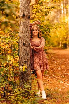 a woman leaning against a tree in the woods