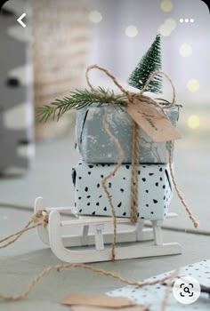 two wrapped presents tied up on a sled with a pine tree in the top