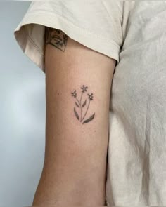 a woman's arm with a small flower tattoo on the left side of her arm