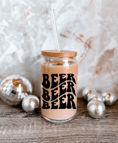 a glass jar with a straw in it sitting on a table next to silver balls