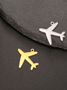 two metal airplanes sitting next to each other on a black tablecloth with a gold and silver charm