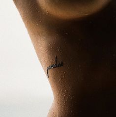 a woman's back with the word paradise written on it and water drops all over her body