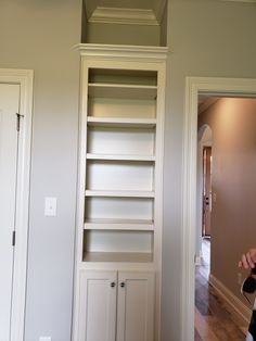 a person taking a photo of a bookcase in a room with white walls and wood floors