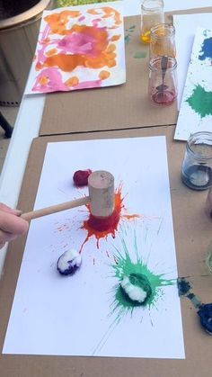 the child is painting on paper with paints