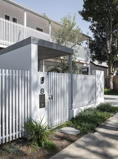 an apartment building with white picket fence and trees