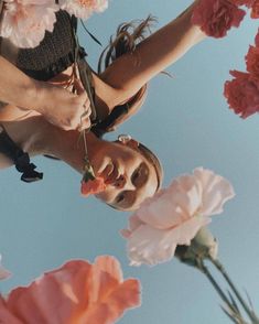 a woman holding flowers up in the air