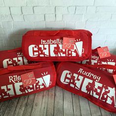 four red bags with white letters on them sitting next to each other in front of a brick wall