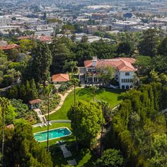 an aerial view of a large house surrounded by trees and houses in the distance with a swimming pool