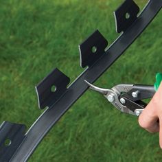 someone is using pliers to cut the side of a metal structure with green grass in the background