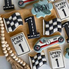 decorated cookies in the shape of race cars and numbers on a wooden board with tassels