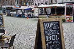 an outdoor market with tables and chairs on the side walk in front of some buildings