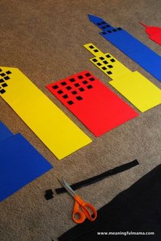 some construction paper cut out to look like blocks and scissors on the floor with tape