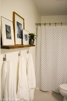 a bathroom with towels hanging on the wall next to a toilet and shower curtain in it