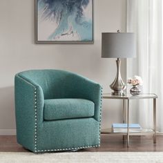 a blue chair sitting in front of a window next to a table with a lamp on it