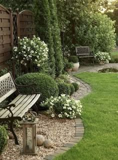 a wooden bench sitting in the middle of a lush green yard next to a stone path