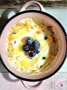 a bowl filled with pudding and blueberries on top of a wooden table next to a spoon