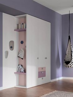 a bedroom with purple walls and white cupboards, two hanging baskets on the wall