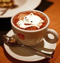 a cappuccino with a cat design in it on a white saucer