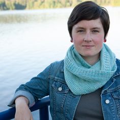 a woman with short hair wearing a blue jean jacket and a scarf around her neck