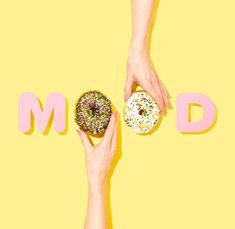 two hands holding doughnuts in front of the word modd on a yellow background