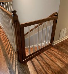 a wooden banister next to a white wall and wood flooring in a home