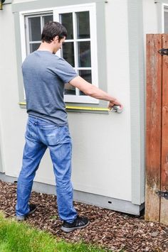 a man in overalls is opening the window on a house that has been built