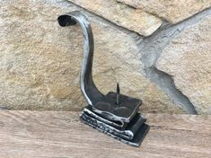 a metal object sitting on top of a wooden table next to a rock face wall