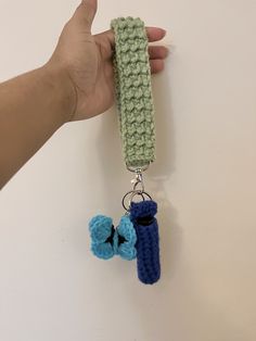 a hand holding a crocheted keychain with two keys attached to it