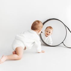 a baby is looking into a mirror at it's own reflection in the mirror