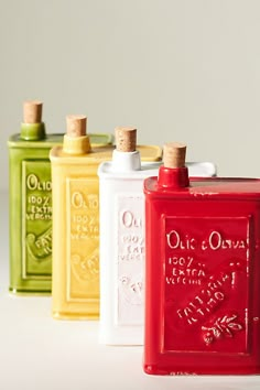 four different colored flasks are lined up in a row on a white surface